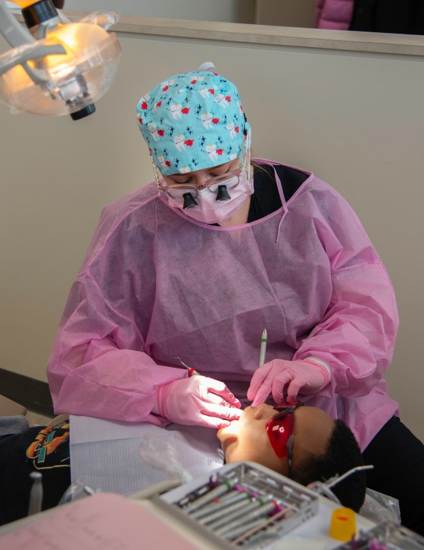 Dental student Angi Gonsiorowski of Hobart cleans the teeth of eight-year-old Alexander Flowers during the annual "Give Kids a Smile" event at Indiana University Northwest in Gary on Saturday, Feb. 15, 2025. (Michael Gard/for the Post-Tribune)