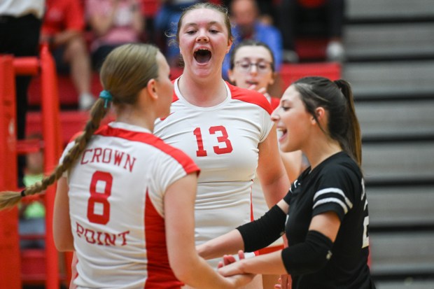 Crown Point middle hitter Ivy Henderson, center, celebrates with teammates Elle Schara, on left, and Bella Del Real during a game against Chesterton on Thursday, Sept. 5, 2024. (Kyle Telechan/for the Post-Tribune)