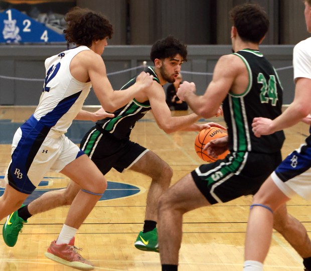 Oak Lawn's Ali Farhan, right, charges with the ball during the boys basketball game against Riverside-Brookfield in Riverside on Saturday, Feb. 8, 2025. (James C. Svehla / for the Daily Southtown)