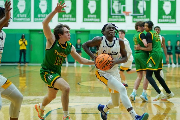 Marian Catholic's Terrell Morton (right), drives to the basket against Providence's Logan Walker (13) during a Class 3A Providence regional semifinal basketball game at Providence Catholic High School in New Lenox on Wednesday, Feb. 26, 2025. (Sean King / for The Daily Southtown)