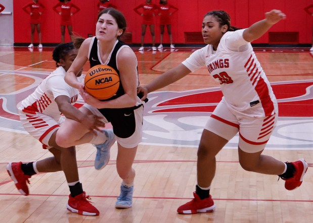 Lincoln-Way West's Caroline Smith (center) goes through Homewood-Flossmoor's Jeriyah McDonald (left) and Ashlynn Magee (right) on her way to the basket during a basketball game in Flossmoor on Tuesday, Feb. 11, 2025. (John Smierciak / Daily Southtown)