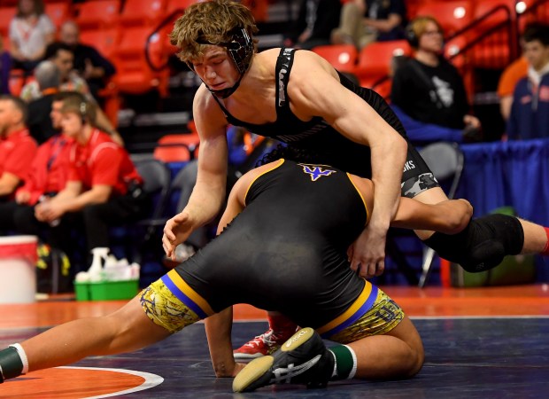 Warren's Royce Lopez (with blue trim) grabs for the legs of West Aurora's Dayne Serio in the 165 pound Class 3A 5th place match at the IHSA Wrestling individual state meet at the University of Illinois' State Farm Arena in Champaign, Saturday Feb. 22, 2025. (Rob Dicker / for the Beacon-News)