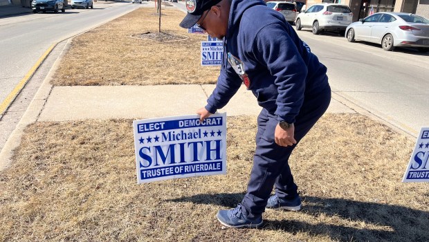 Members of Michael Airhart's mayoral campaign in Riverdale place election signs on a median outside village hall, after village police had ordered their removal on Feb. 25, 2025.(Samantha Moilanen/Daily Southtown)