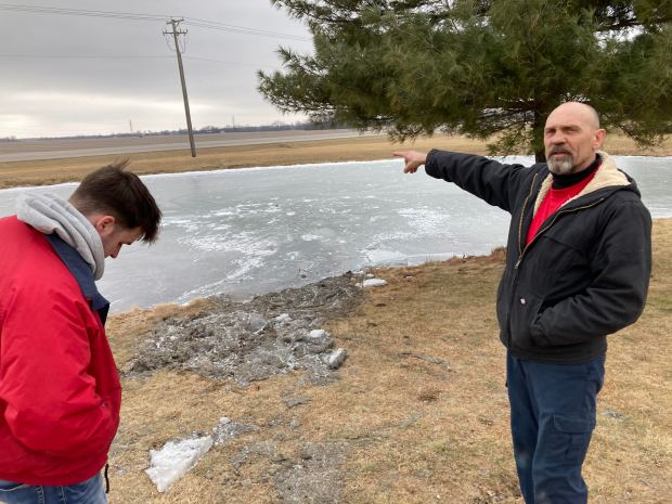 Crete Ace Hardware employee John Minerd, right, points Feb. 11, 2025, to a retention pond where he and co-worker Adam Kroll, left, rescued the driver of a truck that drove onto the frozen pond Saturday night. (Mike Nolan/Daily Southtown)