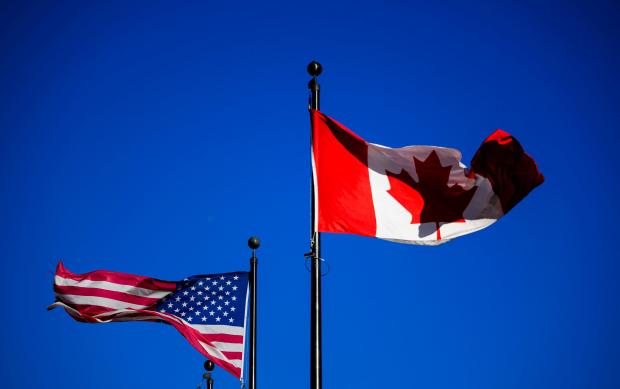 The flags of Canada and the United States fly outside a hotel in downtown Ottawa, on Saturday, Feb. 1, 2025. (Justin Tang/The Canadian Press via AP)