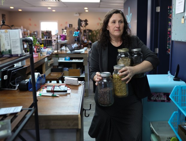 Cheryl Cryer carries jars of herbs and flowers in her shop, Urban Apothecary, on Feb.10, 2025, in Batavia. (Stacey Wescott/Chicago Tribune)