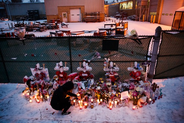 Jasmin Olvera, 22, lights candles next to a memorial outside the Henry Pratt Co. plant where on Friday six people, including the gunman, were fatally shot on Feb. 17, 2019, in Aurora. (Armando L. Sanchez/Chicago Tribune)