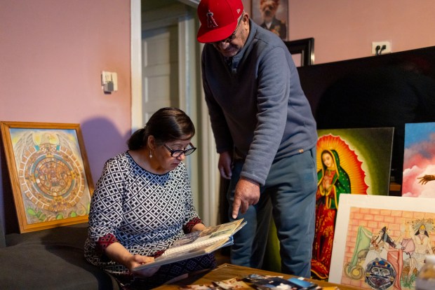 Maria and Joaquin look at pictures of their son, Erick, who was deported to Mexico years ago, while surrounded by some of his artwork at their home in Little Village, Jan. 28, 2025. (Brian Cassella/Chicago Tribune)