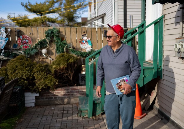 Joaquin walks through is backyard in Little Village while holding photos of his son, Erick, who was deported to Mexico years ago, Jan. 28, 2025. (Brian Cassella/Chicago Tribune)