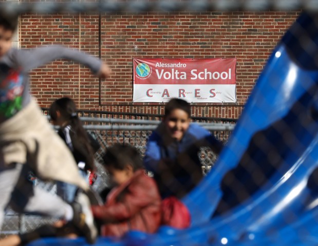 A banner reads, "Alessandro Volta School CARES," near a playground as children play at Volta Elementary School on Feb. 25, 2025. (John J. Kim/Chicago Tribune)