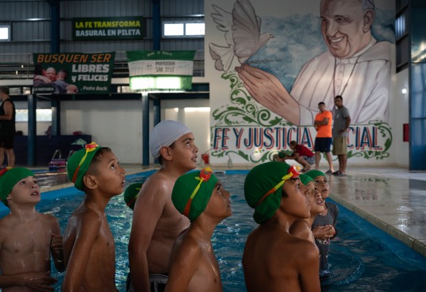 Children listen to a coach during a swimming lesson with a painting of Pope Francis in the background, in San Jose natatorium in Buenos Aires, Argentina on Feb. 18, 2025. (Rodrigo Abd/AP)