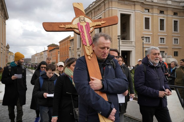 Pilgrims for the jubiliar year 2025 carrying a wooden cricifix arrive in St. Peter's Square at The Vatican on Feb. 14, 2025, hours after Pope Francis was hospitalized to undergo some necessary diagnostic tests and to continue his ongoing treatment for bronchitis. (Alessandra Tarantino/AP)