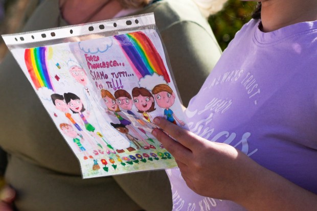 A child holds a drawing reading: "C'mon Pope Francis we are all with you" as she prays outside the Agostino Gemelli Polyclinic in Rome on Feb. 23, 2025, where Pope Francis is hospitalized since Feb. 14. (Gregorio Borgia/AP)