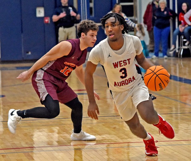 West Aurora's Jaden Edwards drives past Brother Rice's Zach Mikrut. West Aurora defeated Brother Rice in a boys basketball game 56-51 Saturday, Feb. 8, 2025, in Aurora, Illinois. (Jon Langham/for the Beacon-News)