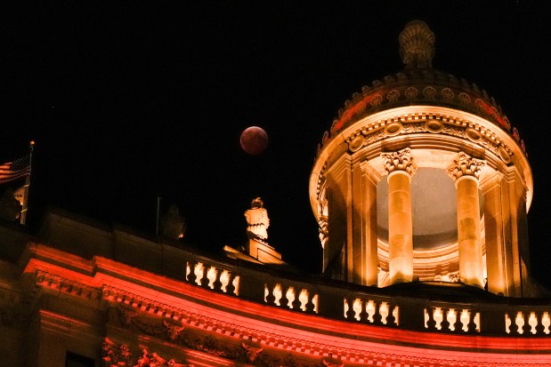 A total lunar eclipse, known as the blood moon, is visible behind the top of London House hotel early Friday, March 14, 2025, in Chicago. (AP Photo/Kiichiro Sato)