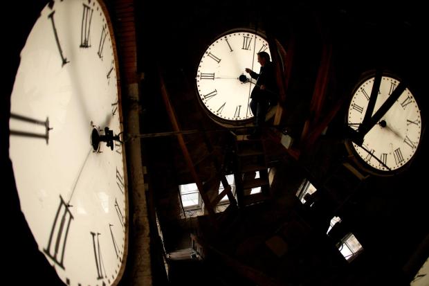 Custodian Ray Keen inspects a clock face before changing the time on the 100-year-old clock atop the Clay County Courthouse, March 8, 2014, in Clay Center, Kansas. (AP Photo/Charlie Riedel)