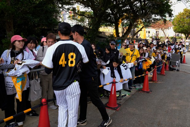 Hanshin Tigers' Hidetoshi Ibaragi gives autographs to baseball fans during their spring training in Ginoza village on Feb. 17, 2025. (AP Photo/Hiro Komae)