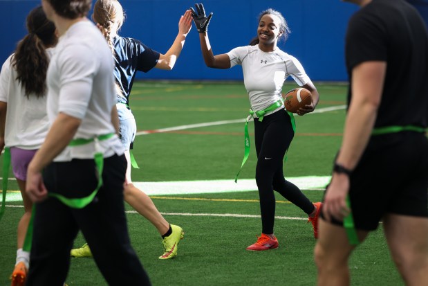 Saniya Shotwell high fives a teammate after getting a first down during a Benedictine University women's flag football team practice on Feb. 21, 2025. (Audrey Richardson/Chicago Tribune)