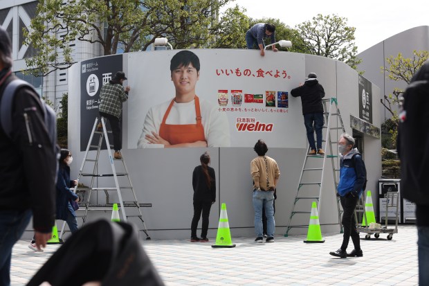 Workers post an outdoor advertisement showcasing Dodgers two-way player Shohei Ohtani outside the Tokyo Dome on March 14, 2025, in Tokyo. (John J. Kim/Chicago Tribune)