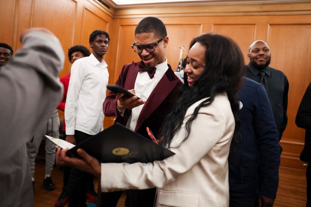 Dyett High School basketball team assistant coach Darrell Bullock takes a photo as principal Dori Butler holds a proclamation honoring their team for their high school state championship in the mayor's ceremonial office at City Hall, March 20, 2025. (Eileen T. Meslar/Chicago Tribune)