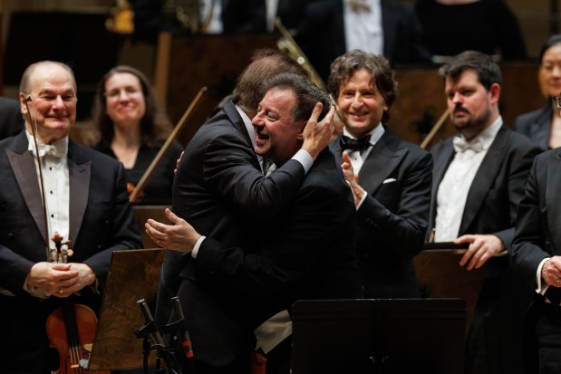 Principal clarinet Stephen Williamson, right, hugs composer Christopher Theofanidis, left, after performing with conductor Gustavo Gimeno and members of the Chicago Symphony Orchestra on March 6, 2025. (Armando L. Sanchez/Chicago Tribune)