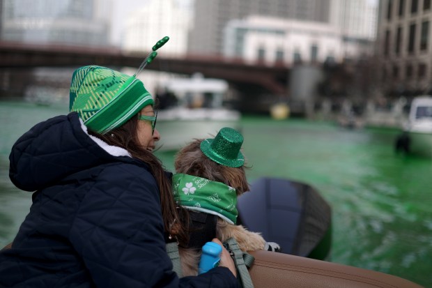 Belyinda Phan and her dog Wookie aboard a boat from the Freedom Boat Club of Chicago go down the Chicago River as it's dyed green by The Chicago Plumbers Union, Chicago Journeymen Plumbers Local 130, to celebrate St. Patrick's Day, March 15, 2025. in Chicago. (Audrey Richardson/Chicago Tribune)