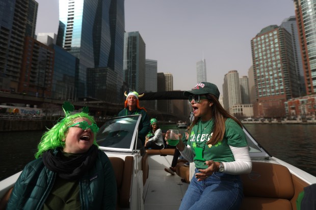 Spectators Kate Liebelt and Rose Gentry aboard a boat from the Freedom Boat Club of Chicago, piloted by captain George Van Geem, go down the Chicago River as it's dyed green by The Chicago Journeymen Plumbers Local 130, to celebrate St. Patrick's Day, March 15, 2025. in Chicago. (Audrey Richardson/Chicago Tribune)