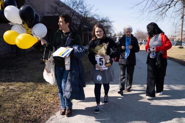 Beatriz Whitford-Rodriguez, right, 13, of Skinner North Classical School, leaves with her father, Ben Whitford, and family, after winning the 2025 Citywide Spelling Bee Championship against other Chicago Public Schools students at Curie Metropolitan High School. (Audrey Richardson/Chicago Tribune)