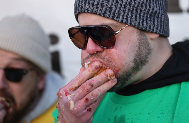 A participant works to finish in the annual paczki eating contest at Bennison's Bakery in Evanston, March 1, 2025. (Chris Sweda/Chicago Tribune)