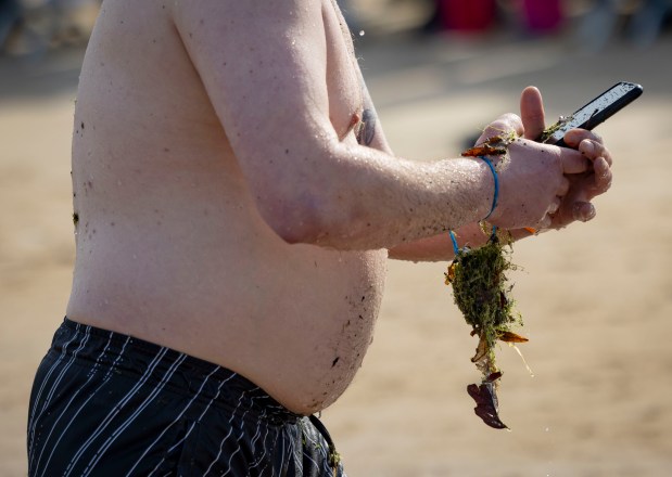 A participant emerges with seaweed after running into Lake Michigan with temperatures in the 20s on March 2, 2025, during the annual Polar Plunge benefitting Special Olympics Illinois. (Brian Cassella/Chicago Tribune)