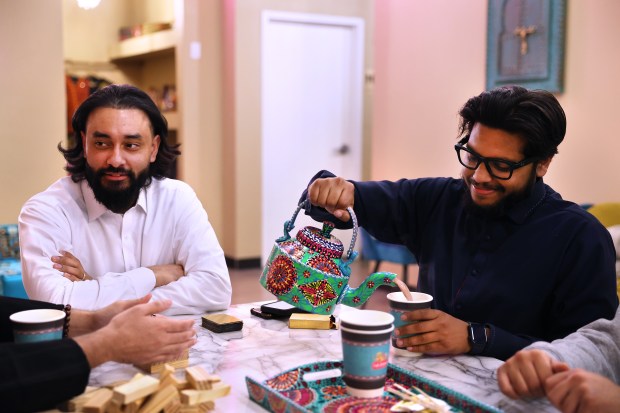 Hassan Javed pours chai for his friends, including Hasan Mohiuddin, left, in the early morning hours at Cafe Bethak in Lombard. (Chris Sweda/Chicago Tribune)