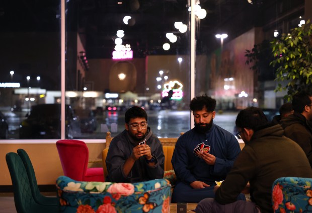 A small group plays the card game UNO in the early morning hours at Cafe Bethak in Lombard, March 16, 2025. (Chris Sweda/Chicago Tribune)