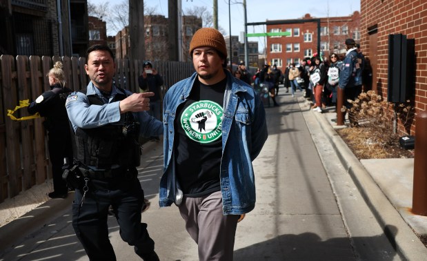 A Chicago police officer detains one of nearly a dozen people, some of them Starbucks baristas, after the group refused to leave the coffee shop at Ridge Avenue and Clark Street in Chicago's Andersonville neighborhood on March 11, 2025. Eleven were arrested for criminal trespassing. (Chris Sweda/Chicago Tribune)