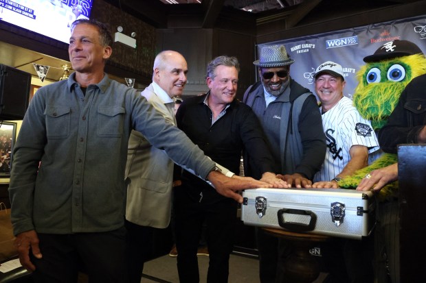 Retired Chicago sports stars gather at Harry Caray's Tavern on Tuesday, March 18, 2025, for the 27th annual toast to Harry Caray. From left: Chris Chelios (Blackhawks), Mike Huff (White Sox), Jeremy Roenick (Blackhawks), Richard Dent (Bears), real estate developer Lee Golub and White Sox mascot Southpaw touch a case containing a baseball from the infamous 1919 World Series, known for the Black Sox scandal. (Terrence Antonio James/Chicago Tribune)