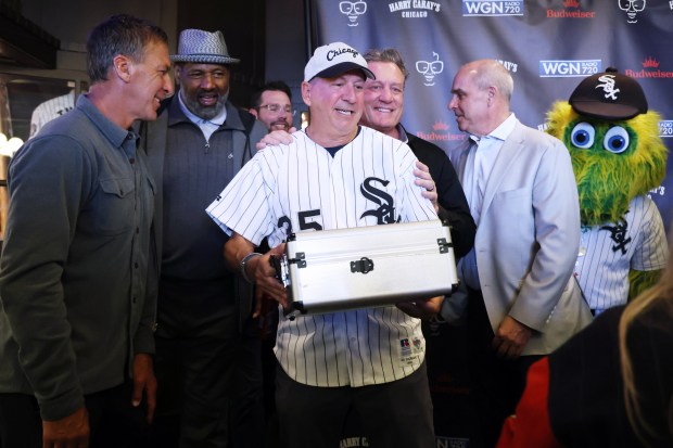 Real estate developer Lee Golub holds a case containing a baseball from the 1919 World Series at Harry Caray's Tavern on Tuesday, March 18, 2025, during the 27th annual toast to Harry Caray. Also seen, from left, are retired athletes Chris Chelios (Blackhawks), Richard Dent (Bears), Jeremy Roenick (Blackhawks), Mike Huff (White Sox) and the White Sox mascot Southpaw. (Terrence Antonio James/Chicago Tribune)