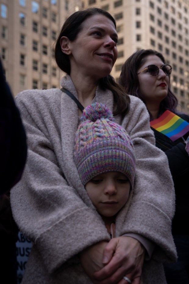 Elizabeth Brown wraps her arms around her daughter, Camilla Brown, 6, as people gather at Daley Plaza and march to Trump Tower for International Women's Day on March 8, 2025. (Audrey Richardson/Chicago Tribune)