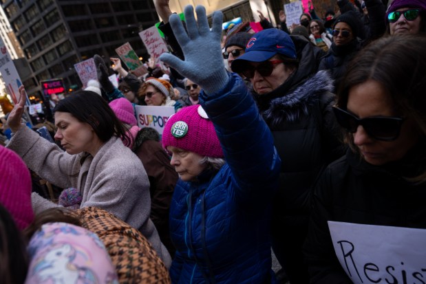 Mary Hobein raises her hand as she participates in a rally at Daley Plaza before marching to Trump Tower for International Women's Day. (Audrey Richardson/Chicago Tribune)