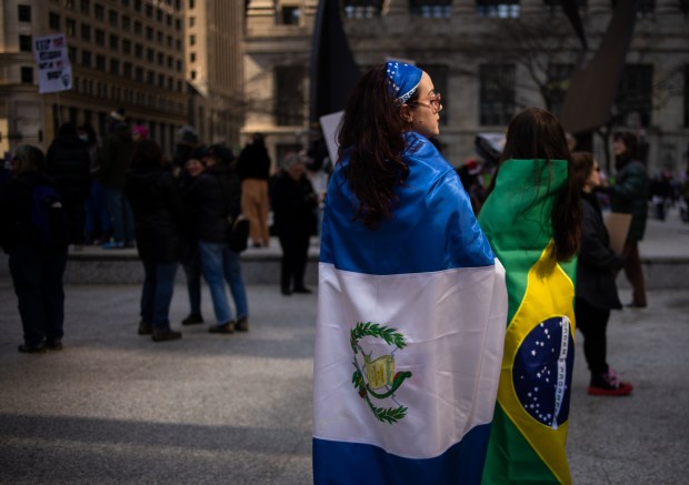 Irene Mendez, left, wears a Guatemala flag with her friend Miriam Balanzar wearing a Brazil flag at Daley Plaza before marching to Trump Tower for International Women's Day. (Audrey Richardson/Chicago Tribune)