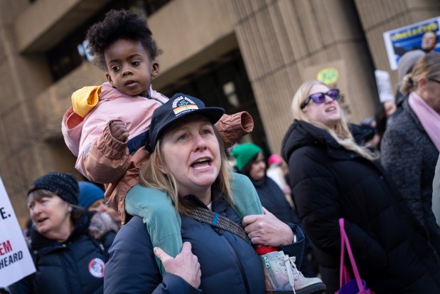 Zonique Yeager, sits on her mother, Emily Thies' shoulders as thousands march to Trump Tower for International Women's Day on March 8, 2025. (Audrey Richardson/Chicago Tribune)