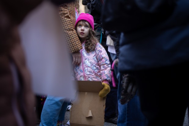 Madeleine Giuca Pront, 5, looks up as people gather at Daley Plaza before marching to Trump Tower for International Women's Day. (Audrey Richardson/Chicago Tribune)