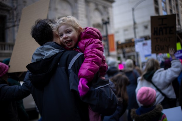 Elise M., 3, is carried by her father, Mike M., during a march to Trump Tower for International Women's Day. (Audrey Richardson/Chicago Tribune)