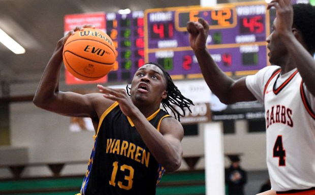 Warren's Javerion Banks (13) goes up past DeKalb's Marquise Bolden (4) for a layup. Warren defeated DeKalb 60-49 in the boys basketball Class 4A Waukegan Sectional semifinal at Waukegan High School, Tuesday, March 4, 2025. (Rob Dicker / for the News-Sun)