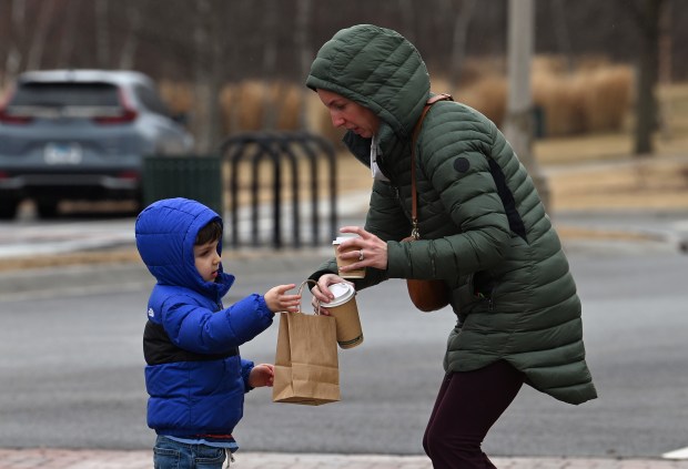 Helping son John Reedy, 4, of Northbrook with his apple juice and a bag holding purchases is parent Abby Reedy at Elawa Farm Winter Market in Lake Forest on March 7, 2025. (Karie Angell Luc/Lake County News Sun)