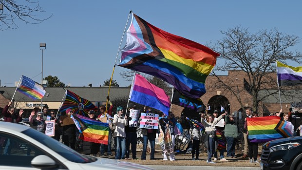 Holding the largest flag is Kristal Larson of Hainesville, Avon Township clerk, the first transgender official elected in Lake County, and executive director of the LGBTQ+ Center Lake County of Grayslake at the Rally for Love, Protest for Love event in Buffalo Grove on Saturday, March 8, 2025. (Karie Angell Luc/Pioneer Press)