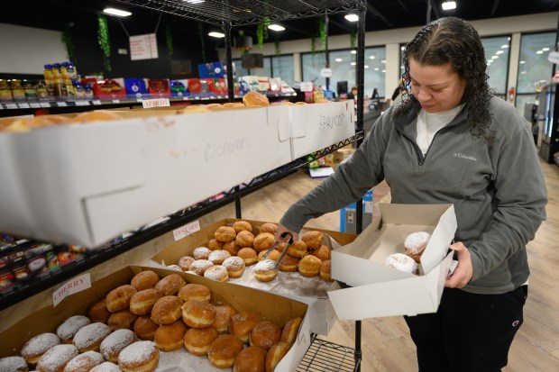 Hammond resident Noemi Flores picks out paczki from a display at Carpathia Deli in Schererville as shoppers stock up on the pastries for Paczki Day on Tuesday, March 4, 2025. (Kyle Telechan/for the Post-Tribune)