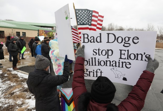 Kathleen Gallion holds a sign that reads, "Bad Doge Stop Elon's Billionaire Grift" during a rally to protest ongoing National Park Service cuts outside the Indiana Dunes Visitor Center Saturday, March 1, 2025, in Porter, Indiana. (John J. Kim/Chicago Tribune)