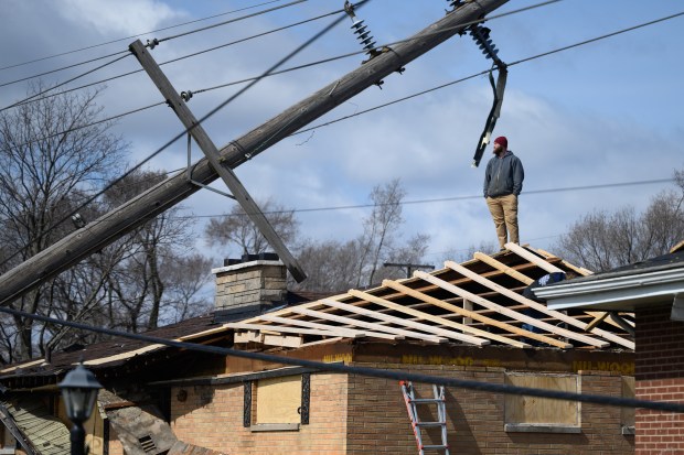 A worker stands atop a damaged home in Gary the day after severe storms hit the west side of the city on Thursday, March 20, 2025. (Kyle Telechan/for the Post-Tribune)