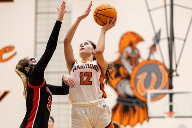 Lincoln-Way West's Caroline Smith (12) goes to the basket as Lincoln-Way Central's Brooke Baechtold (23) tries to stop her during a SouthWest Suburban Conference game in New Lenox on Thursday, Dec. 19, 2024. (Vincent D. Johnson / for the Daily Southtown)