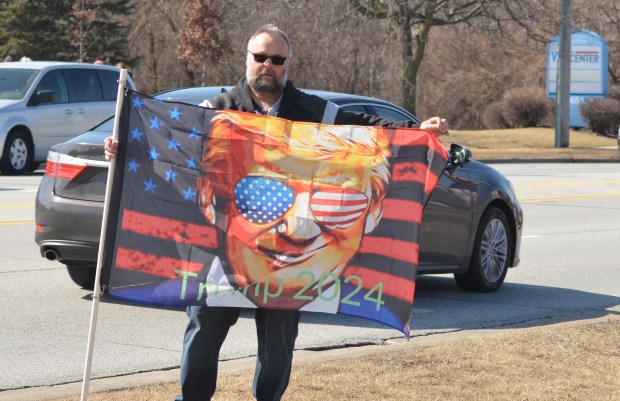 Mike Piotrowski, of Chicago, holds a Donald Trump flag to "protest the protesters" Saturday across the street from the Orland Park Tesla dealership. (Jeff Vorva/for the Daily Southtown)