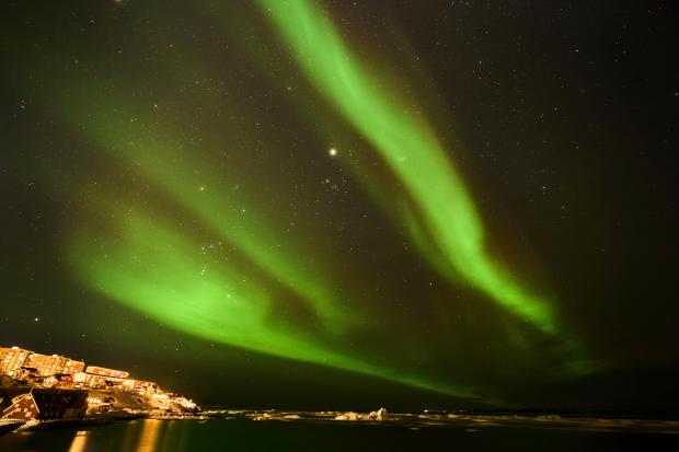 The northern lights appear over homes in Nuuk, Greenland, Monday, Feb. 17, 2025. (AP Photo/Emilio Morenatti)